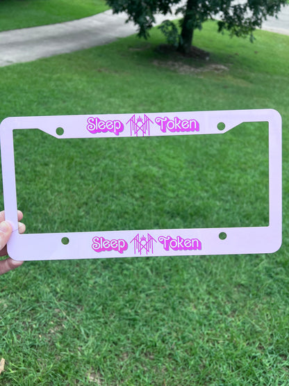 KimTheGrimm Sleep Token Barbie pink sublimated license plate frame held outside in grass background.⁠