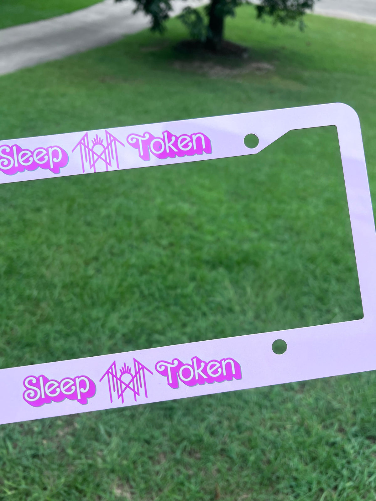 KimTheGrimm Sleep Token Barbie pink sublimated license plate frame held outside in grass background.⁠
