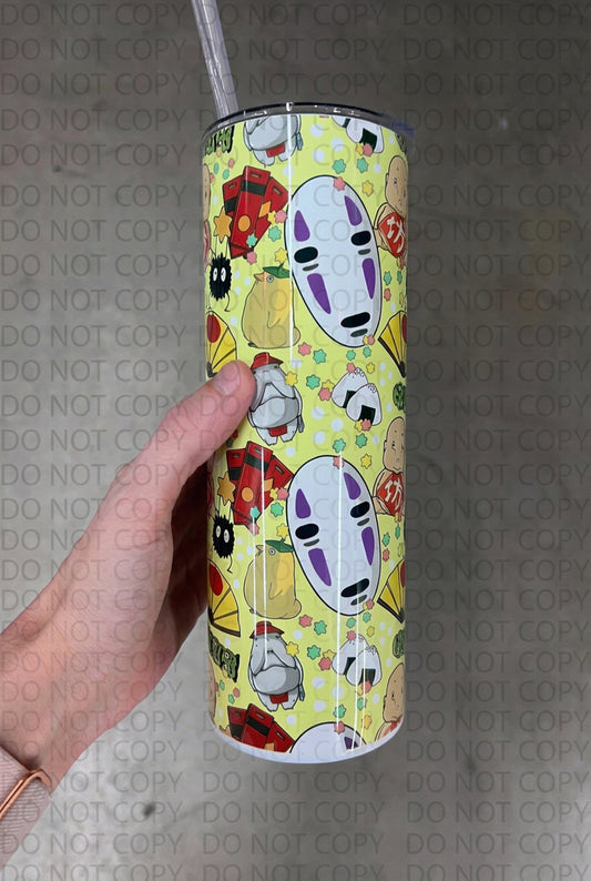 A hand holding a custom pastel yellow 20oz tumbler featuring a repeating Studio Ghibli pattern with No-Face, soot sprites, and Boh.