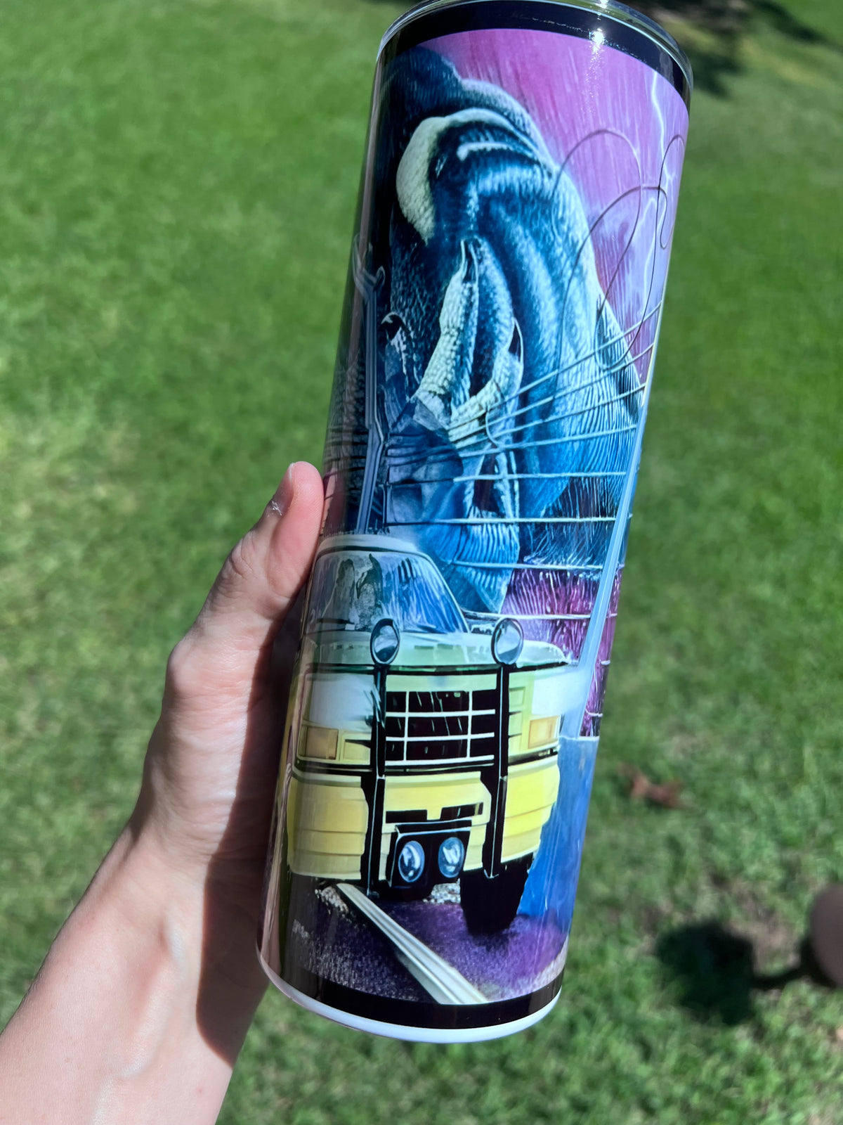 Retro 90s Jurassic Park 20oz skinny tumbler featuring a neon-purple sci-fi wrap with a T-Rex head and tour SUV.⁠