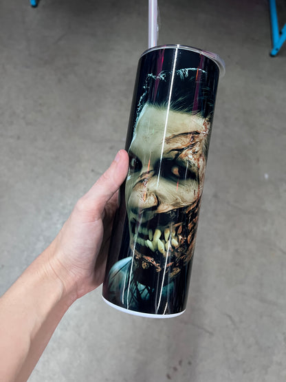 A hand holding a custom black tumbler featuring the word "Decades" in large, gold gothic lettering with "Motionless In White" printed vertically next to it, fading into an eerie green bottom.