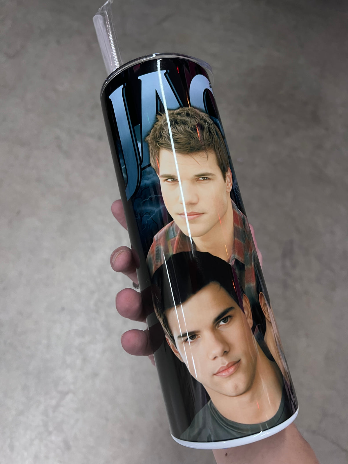 A hand holding a custom Twilight tumbler featuring a multi-image collage of Jacob Black set against a dark background with blue lightning strikes.