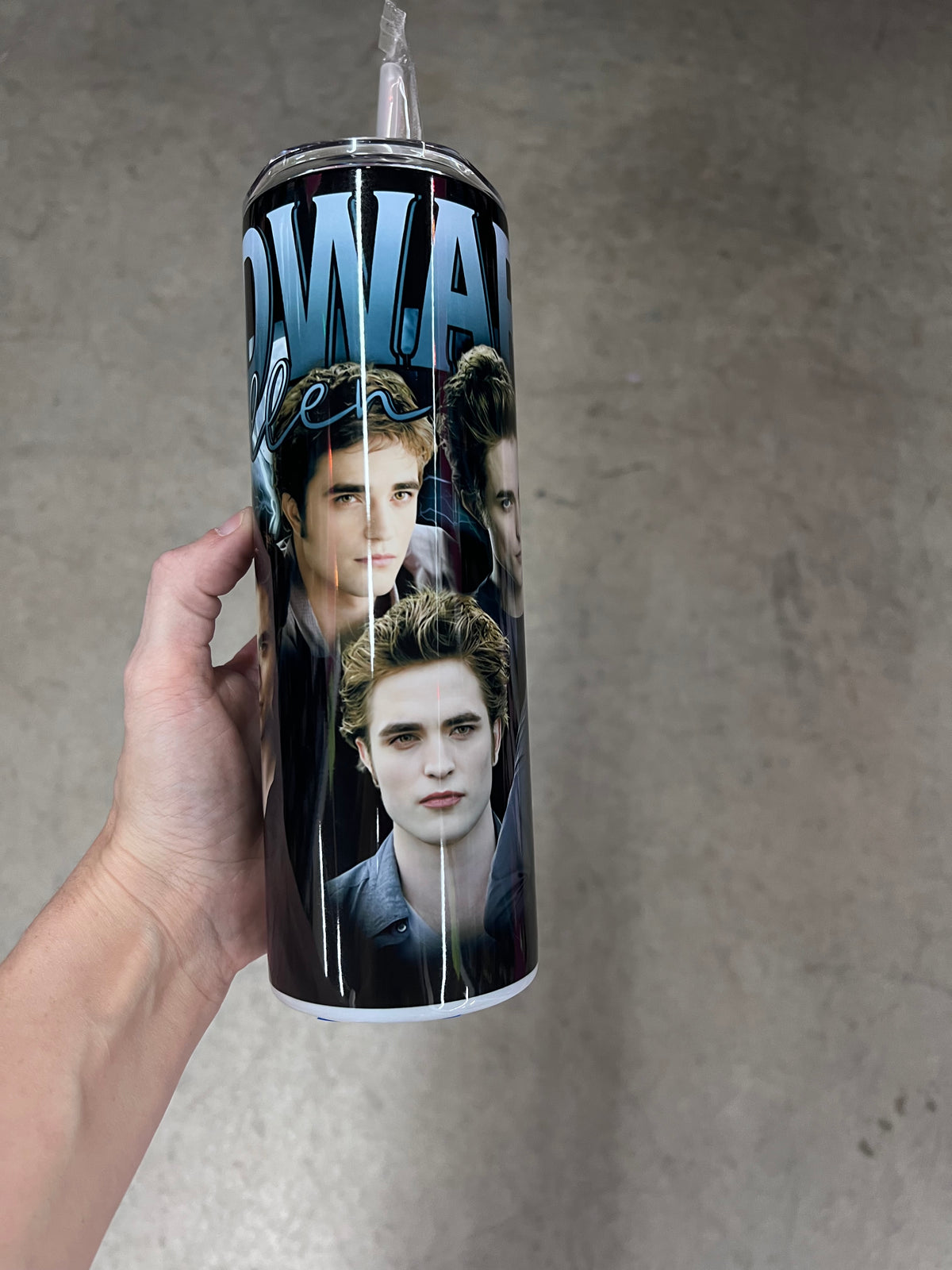 A hand holding a custom Twilight tumbler featuring the name "EDWARD" in bold blue text with "Cullen" in a cursive script, layered over an image of Edward Cullen in a black v-neck shirt.