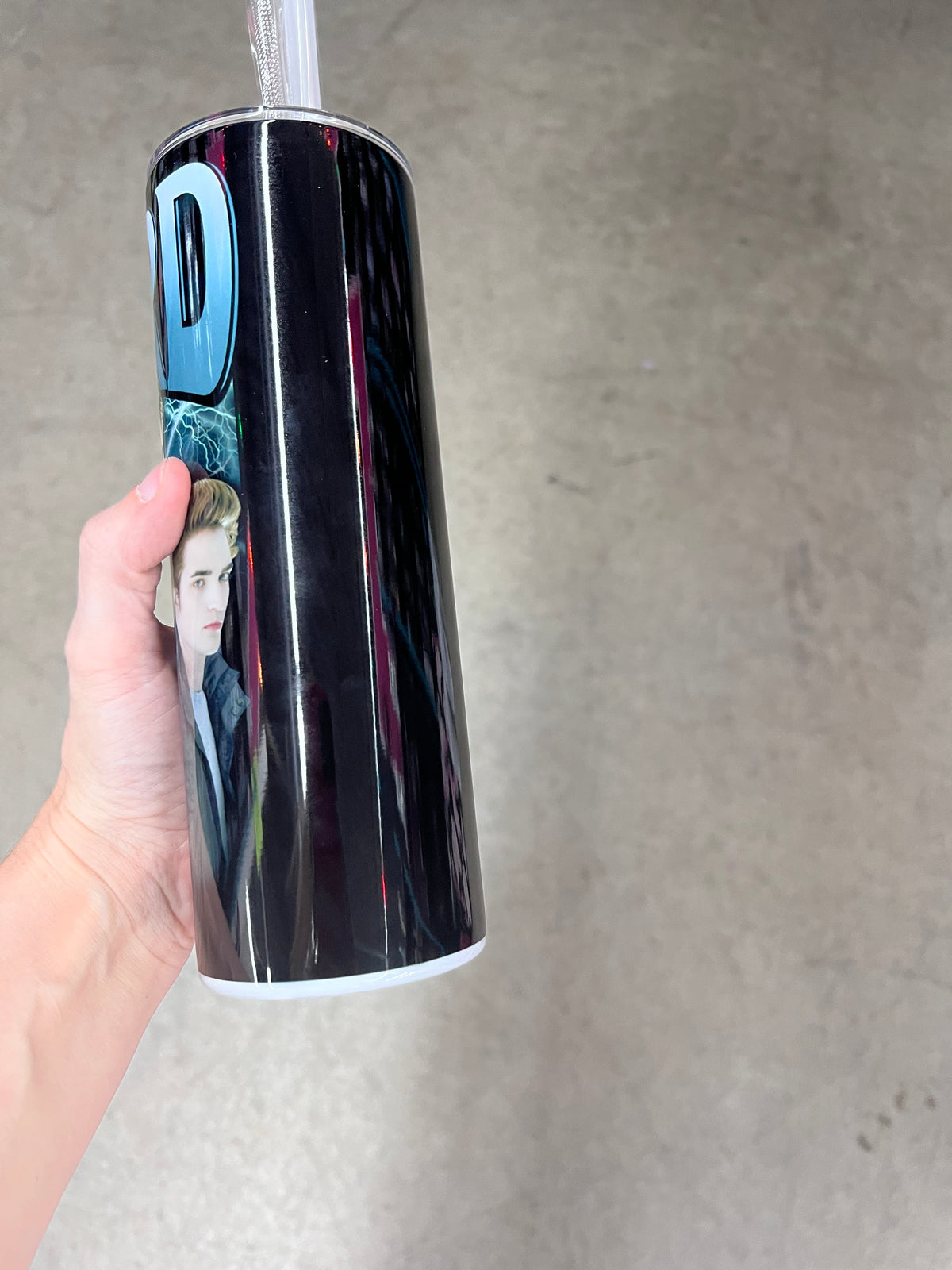 A hand holding a custom Twilight tumbler featuring the name "EDWARD" in bold blue text with "Cullen" in a cursive script, layered over an image of Edward Cullen in a black v-neck shirt.